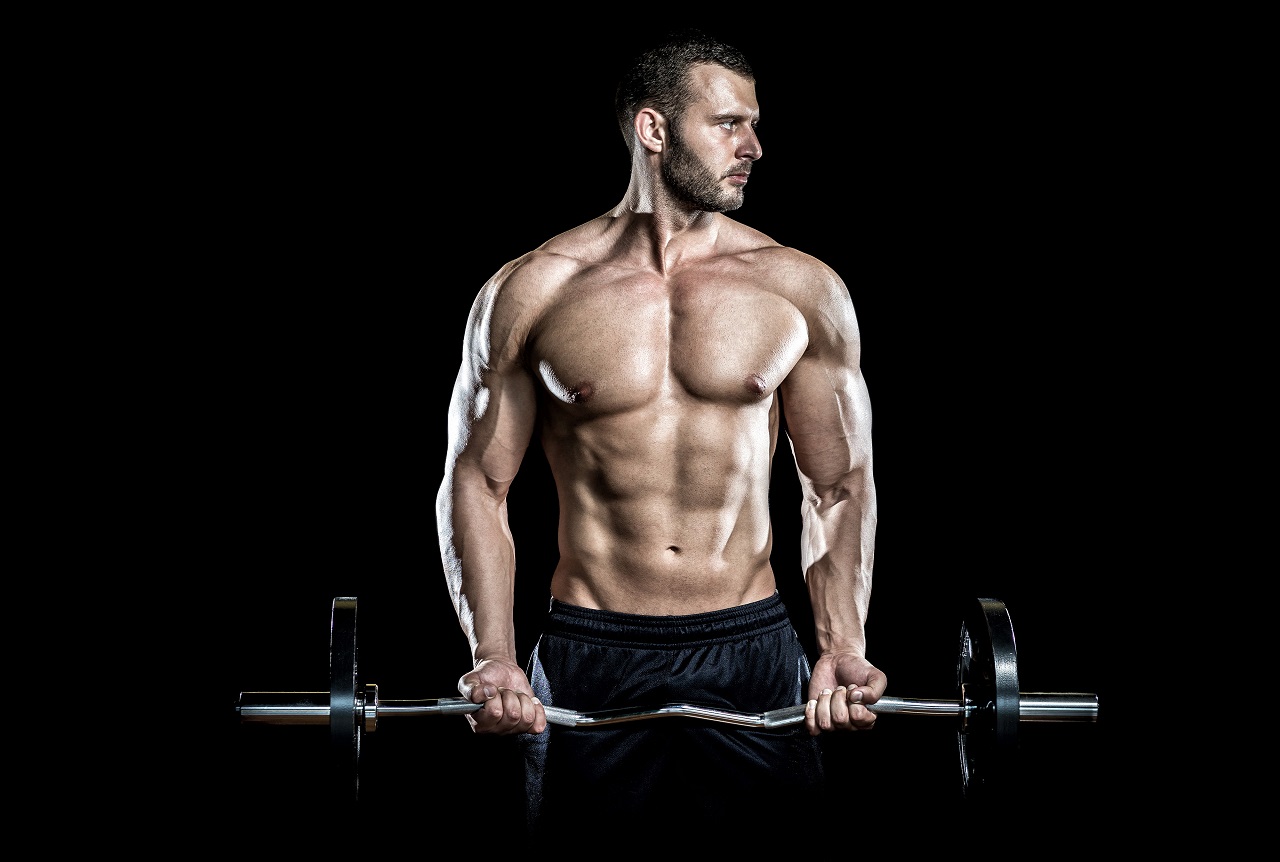 Man doing weight lifting in gym on black background.