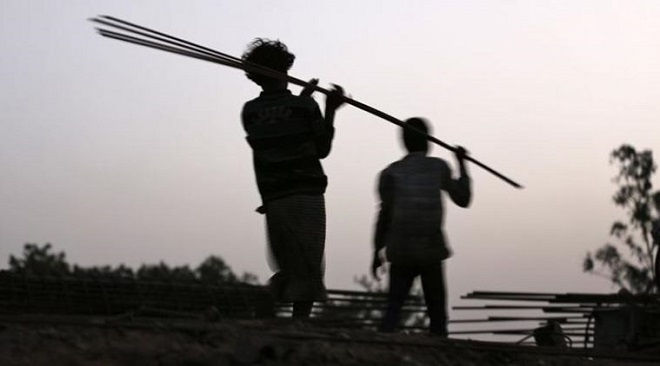 Labourers carry iron rods at the construction site of a flyover on the outskirts of the western Indian city of Ahmedabad